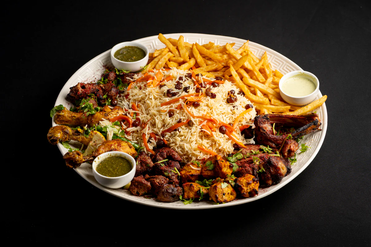 A sharing platter of Kabuli pulao ringed with lamb chops, chicken and beef skewers, fries and green chutney.
