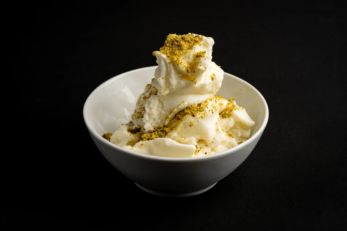 Sheryakh, Afghan ice cream heaped in a white bowl and scattered with crushed pistachio.